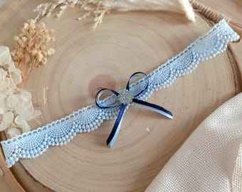 May include: A light blue lace garter with a navy blue satin bow and a small jeweled embellishment.