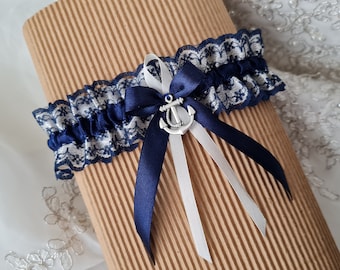 May include: A white and navy blue lace garter with a silver anchor charm and white and navy blue satin ribbons.