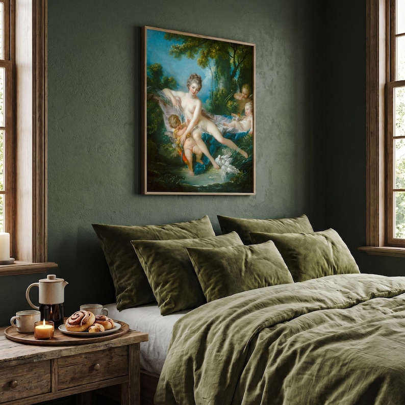 May include: A framed rectangular wall art print featuring a classical oil painting of a reclining figure surrounded by cherubs in a lush forest setting, displayed above a bed with olive green bedding and a wooden nightstand with a candle.