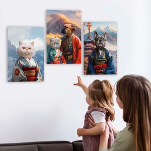 May include: Three framed pet portraits in a Japanese-inspired style. The portraits feature a white cat, a gray cat, and a brown dog wearing traditional Japanese clothing. The portraits are hanging on a white wall.