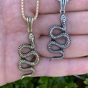 May include: Two silver snake necklaces with a box chain. One snake is gold and the other is silver.