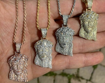 May include: Four Jesus pendants on rope chains. The pendants are made of silver, gold, and rose gold and are encrusted with clear cubic zirconia stones.