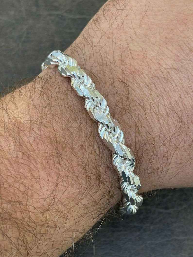Puede incluir: Un brazalete de cadena de cuerda de plata con un dise&ntilde;o trenzado.