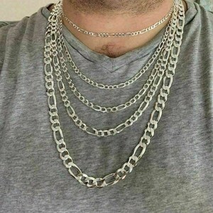 May include: A set of five silver chain necklaces of varying lengths and widths. The chains are all made of a classic figaro design.
