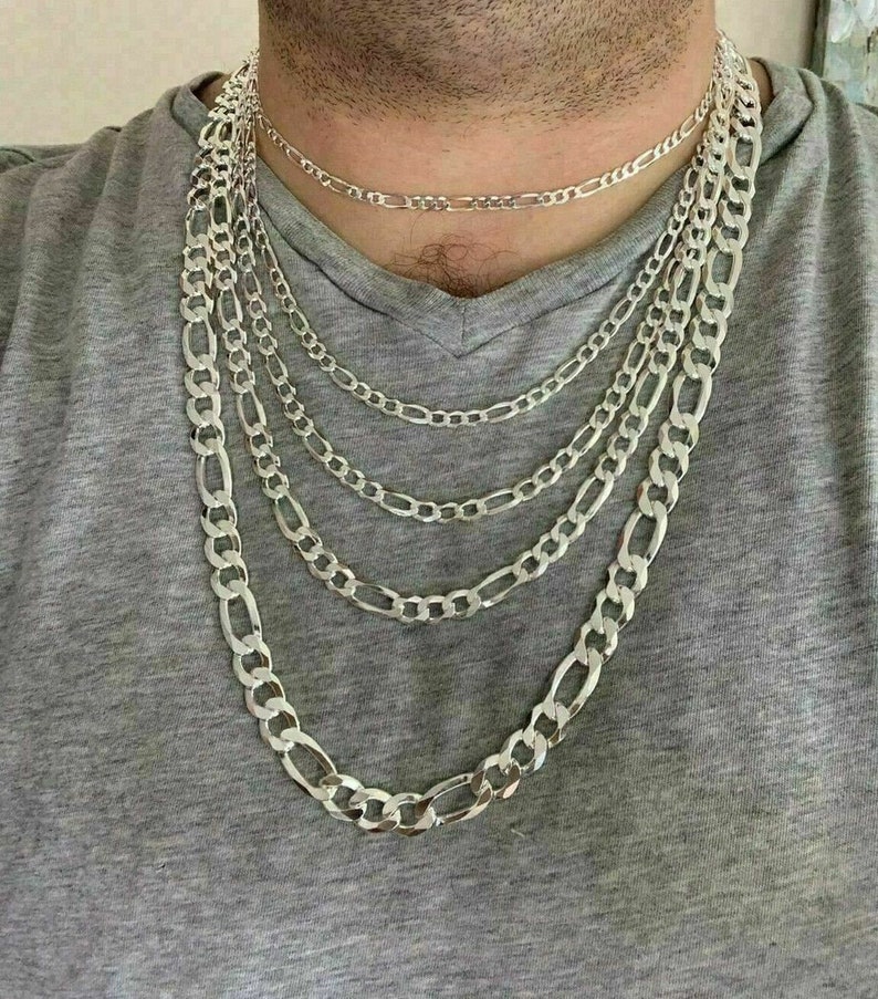 May include: A set of five silver chain necklaces of varying lengths and widths. The chains are all made of a classic figaro design.