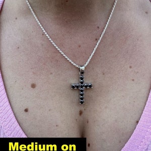 May include: A silver 18 inch rope chain necklace with a black cubic zirconia cross pendant. The text "Medium on 2mm 18" rope" is visible at the bottom of the image.