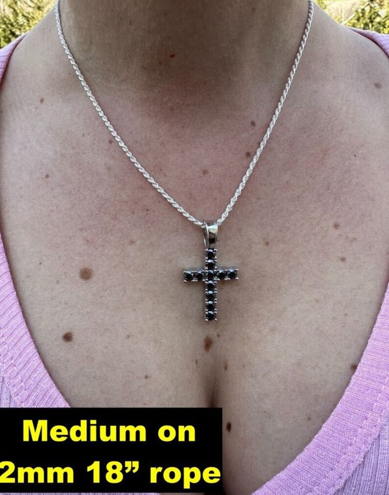 May include: A silver 18 inch rope chain necklace with a black cubic zirconia cross pendant. The text "Medium on 2mm 18" rope" is visible at the bottom of the image.