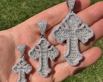 Puede incluir: Tres colgantes de cruz de plata con diamantes de baguette. Las cruces son de diferentes tamaños y todas están engastadas en plata.