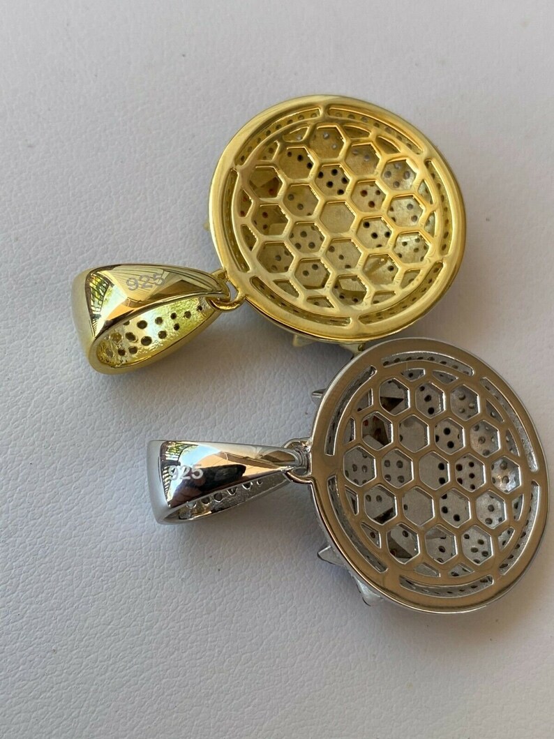 Puede incluir: Dos colgantes, uno dorado y otro plateado, con un dise&ntilde;o circular que presenta un patr&oacute;n de panal. Ambos colgantes tienen una anilla con la inscripci&oacute;n "925" en la parte posterior.