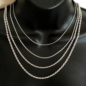 May include: Four silver rope chains of varying thicknesses, layered on a black mannequin bust.