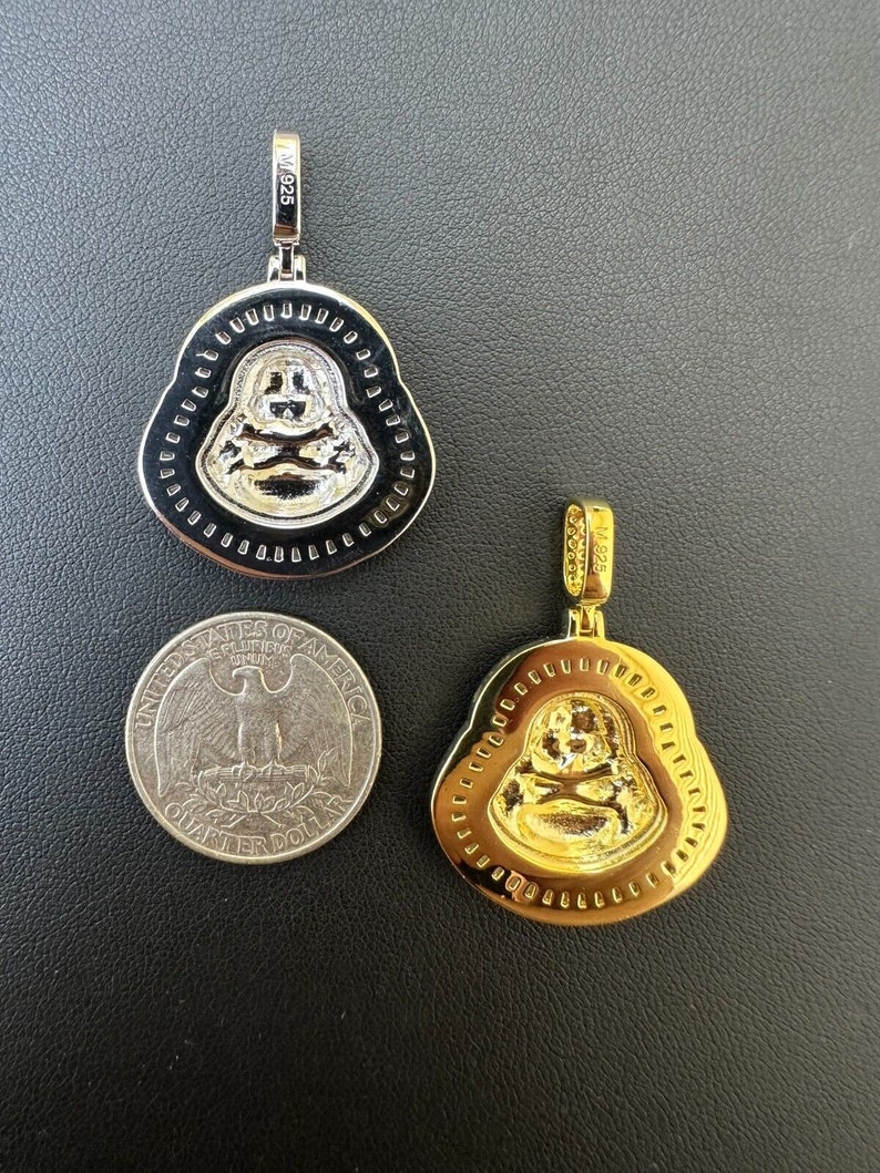 May include: Two Buddha pendant necklaces, one silver-toned and one gold-toned, with a quarter for size comparison. The pendants feature a smiling Buddha design with a skull and crossbones. The silver pendant is marked "M925".