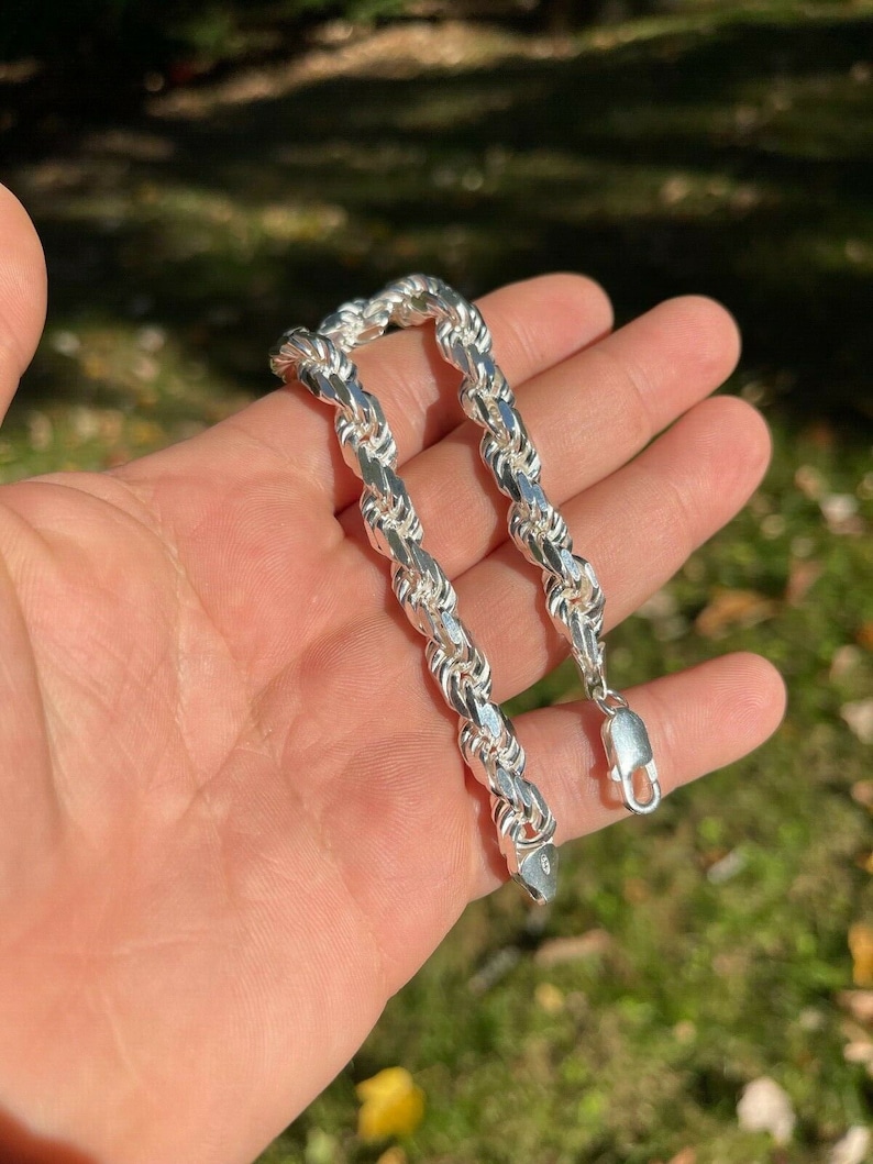 Puede incluir: Un brazalete de cadena de cuerda de plata con cierre de langosta. El brazalete est&aacute; hecho de una cadena gruesa y trenzada.