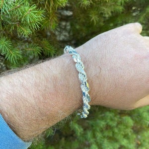 Puede incluir: Un brazalete de cadena de cuerda de plata con un dise&ntilde;o de corte de diamante.