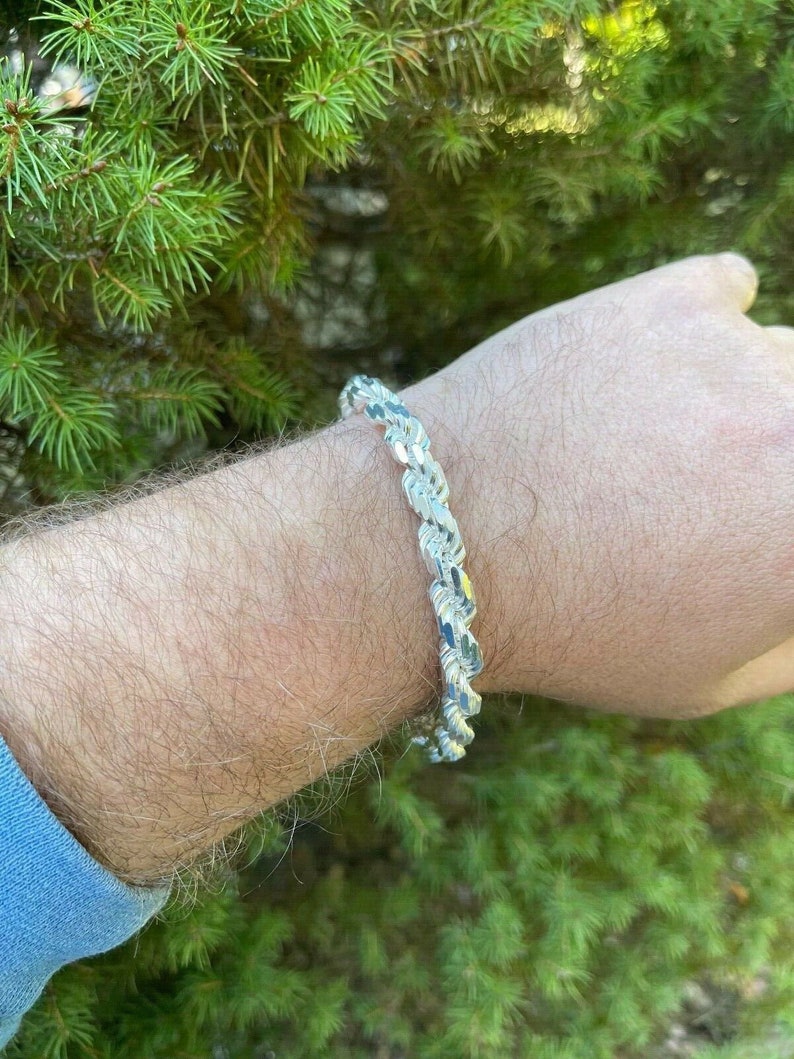 Puede incluir: Un brazalete de cadena de cuerda de plata con un dise&ntilde;o de corte de diamante.