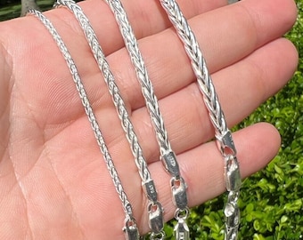 May include: Four silver chains of varying lengths and widths. The chains are braided and have a polished finish. The chains are labeled with their size in millimeters.