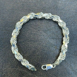 Puede incluir: Un brazalete de cadena de cuerda de plata con cierre de langosta.