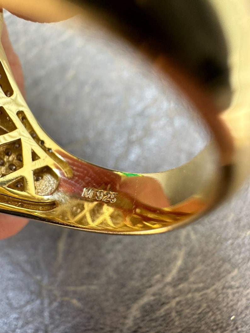 Puede incluir: Primer plano del interior de un anillo de oro con la inscripci&oacute;n "M 925" en la banda.