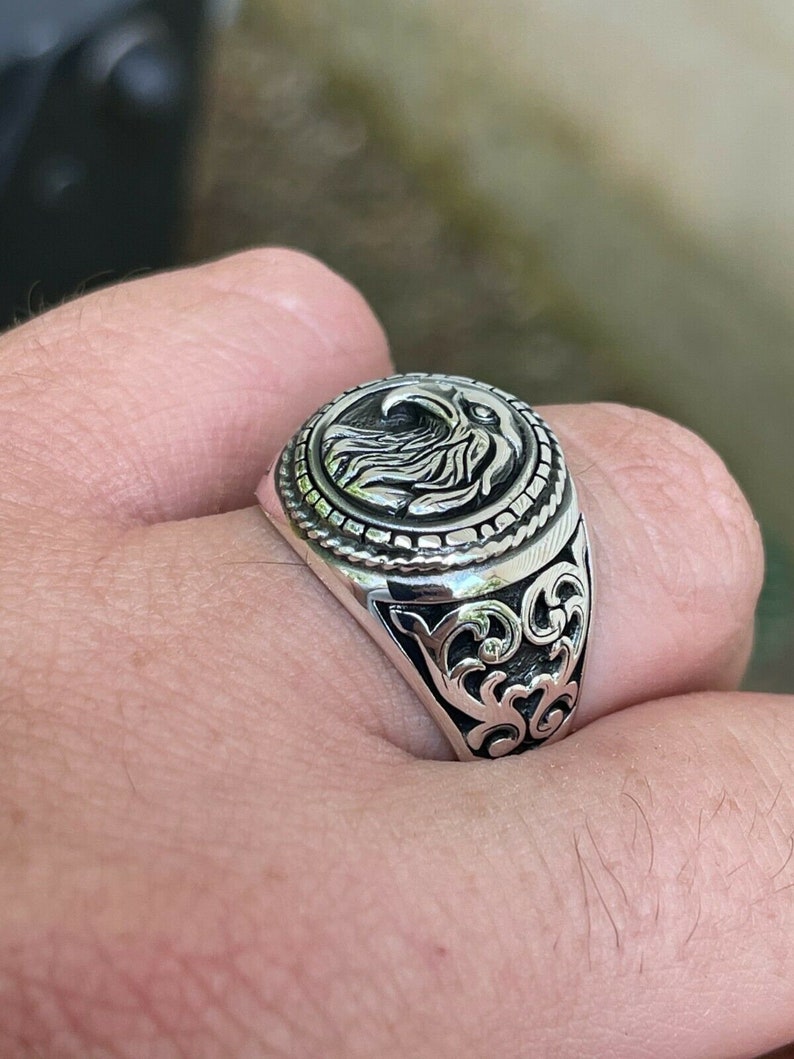 Puede incluir: Un anillo de plata con un dise&ntilde;o de &aacute;guila en la parte superior. El anillo tiene un dise&ntilde;o detallado y adornado en la banda.