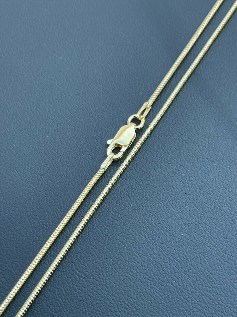 Puede incluir: Un collar de cadena de oro con cierre de langosta. La cadena es de estilo serpiente.