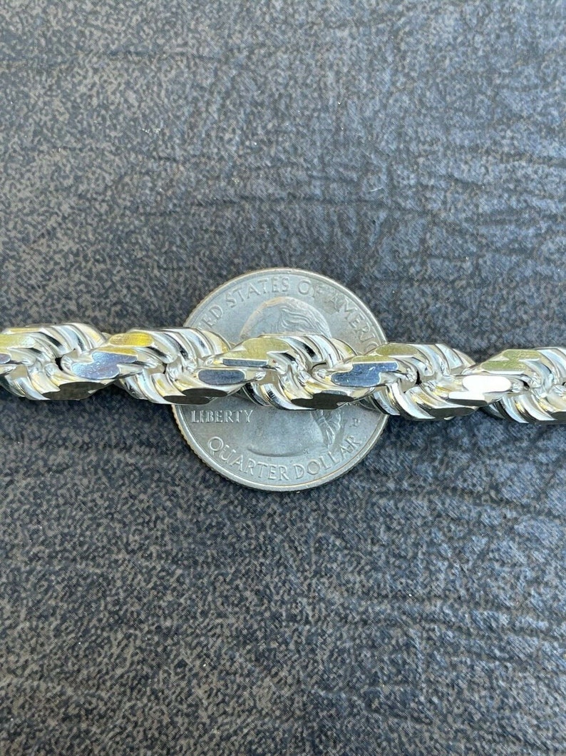 Puede incluir: Un collar de cadena de cuerda de plata con una moneda de veinticinco centavos de d&oacute;lar estadounidense como referencia de tama&ntilde;o. La cadena est&aacute; hecha de un dise&ntilde;o de cuerda trenzada gruesa.