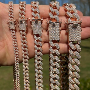 May include: Five gold-tone Cuban link chains with diamond accents. The chains are of varying lengths and widths.