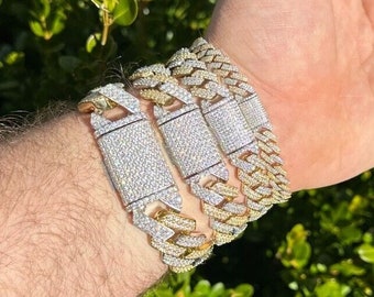 May include: Four gold and silver chain bracelets with diamond-like accents. The bracelets are stacked on a person's wrist.
