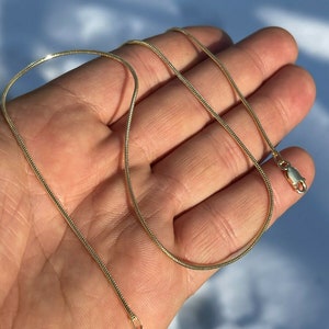 Puede incluir: Un collar de cadena de serpiente de oro con cierre de broche.