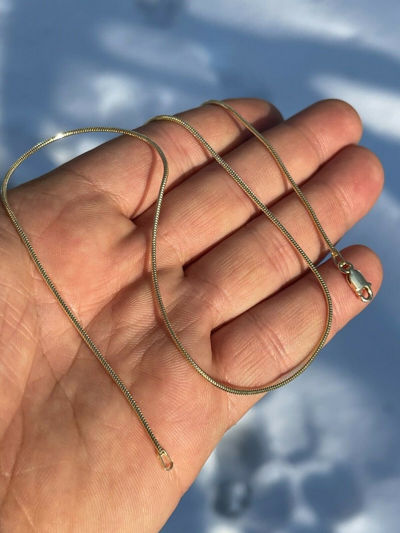 Puede incluir: Un collar de cadena de serpiente de oro con cierre de broche.