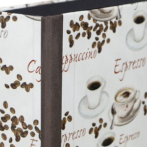 Könnte beinhalten: Ein weißer Ordner mit braunem Rücken und einem Kaffeekornmuster. Der Ordner trägt die Aufschriften "Espresso", "Cappuccino" und "Coffee".