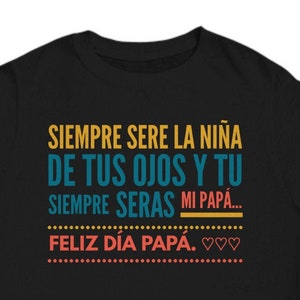 May include: Black t-shirt with text in Spanish. The text reads "SIEMPRE SERE LA NIÑA DE TUS OJOS Y TU SIEMPRE SERAS MI PAPÁ... FELIZ DÍA PAPÁ." in yellow, teal, and coral colors. The design includes hearts.