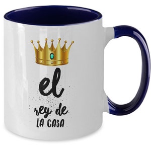 Puede incluir: Taza de cer&aacute;mica blanca con interior y asa azul marino. La taza presenta un dise&ntilde;o de corona dorada con una gema verde y el texto "el rey de LA CASA" en negro. Un regalo perfecto para el rey de la casa.