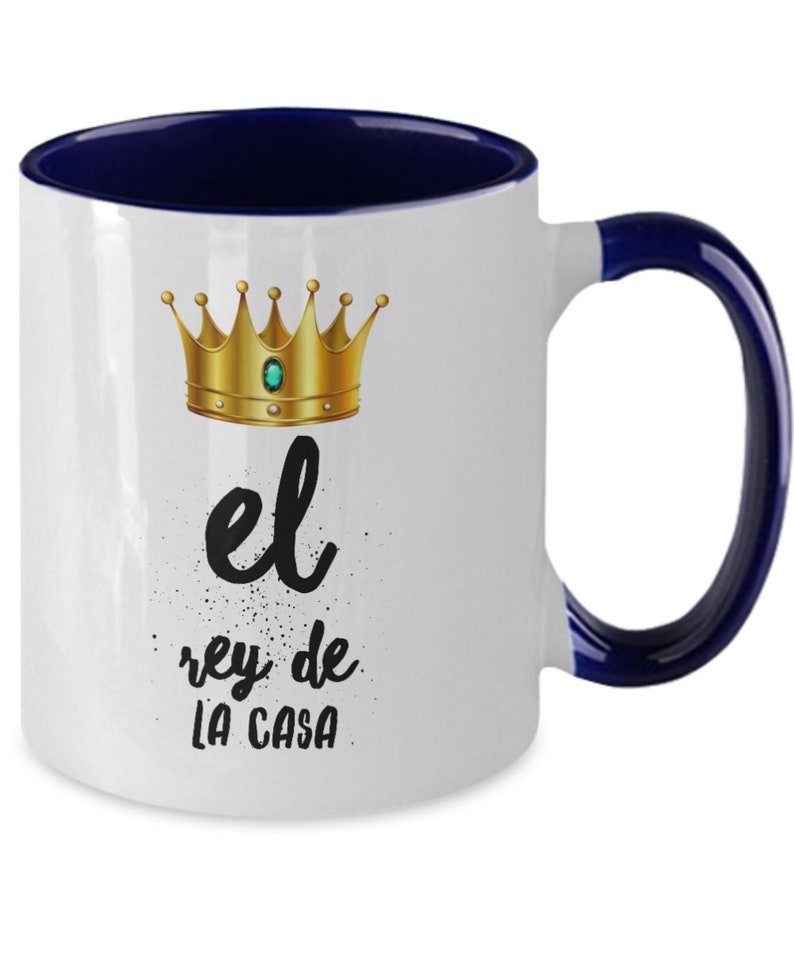 Puede incluir: Taza de cer&aacute;mica blanca con interior y asa azul marino. La taza presenta un dise&ntilde;o de corona dorada con una gema verde y el texto "el rey de LA CASA" en negro. Un regalo perfecto para el rey de la casa.