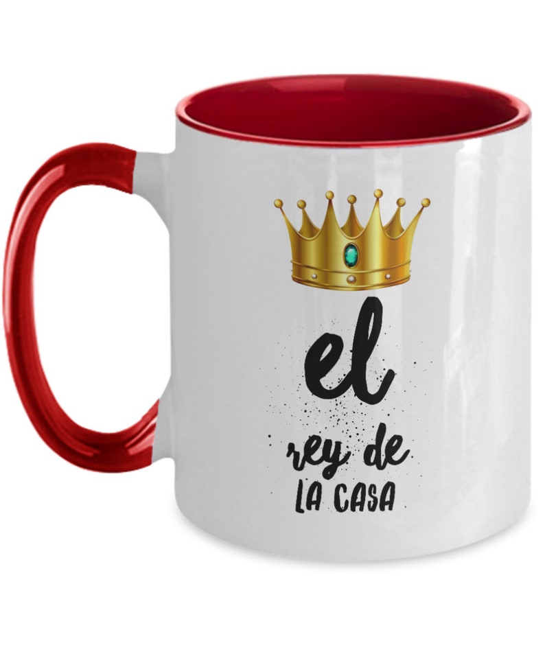 Puede incluir: Taza de cer&aacute;mica blanca con interior y asa rojos. La taza presenta una corona dorada con una gema verde y el texto "el rey de la casa" en escritura negra.