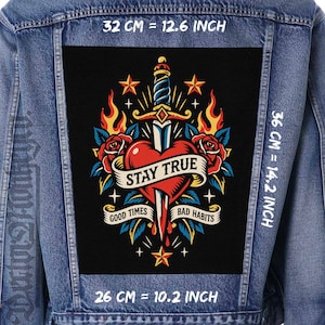 Pode incluir: Um casaco de ganga azul com um grande emblema retangular nas costas com uma ilustração de um punhal a atravessar um coração vermelho, rodeado por chamas, rosas e estrelas. O texto diz STAY TRUE, GOOD TIMES e BAD HABITS. Mede 32 cm por 36 cm por 26 cm.