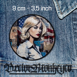 Könnte beinhalten: Ein runder Patch mit einer Frau mit blonden Haaren und rotem Lippenstift. Sie trägt ein weißes Hemd und steht vor einer amerikanischen Flagge. Der Patch hat einen Durchmesser von 9 cm.