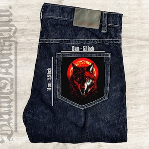 Può includere: Una tasca di jeans blu scuro con una toppa da stirare rossa e nera che presenta un lupo che ulula alla luna rossa. La toppa misura 14 cm per 13 cm.