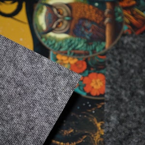 Op de afbeelding: Een close-up van een decoratief textiel met een uilenontwerp. De uil is afgebeeld met bruine en oranje veren, omringd door bloemelementen in tinten rood en groen. De achtergrond is een mix van geel en donkerblauw.