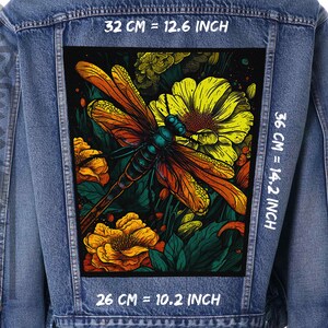 Könnte beinhalten: Eine Jeansjacke mit einem bunten gestickten Patch, der eine Libelle und Blumen zeigt. Der Patch misst 32 cm x 36 cm.