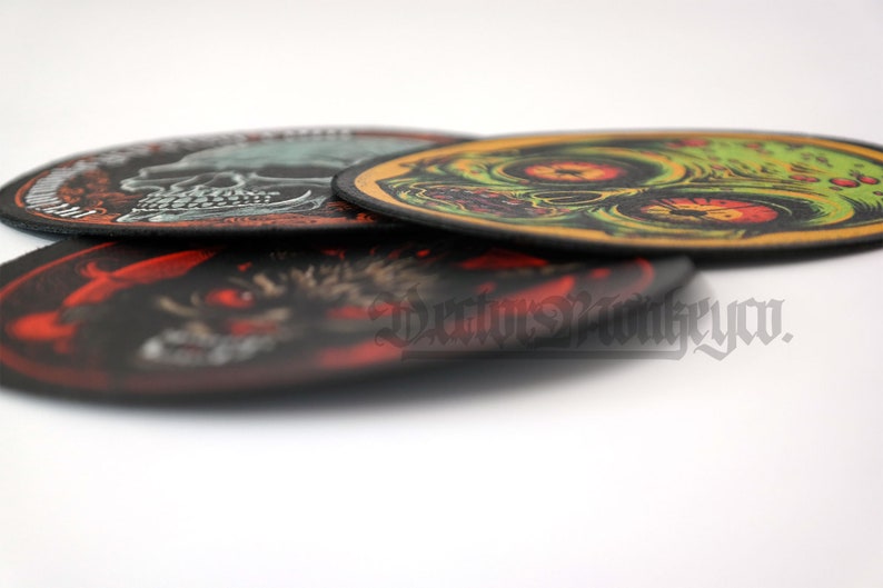 May include: A stack of four circular patches with various designs. The top patch features a green and yellow zombie skull. The bottom patch has a red and black wolf design. The text "Darius Monkeyco" is visible.