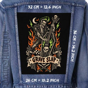 May include: A blue denim jacket featuring a large rectangular back patch with a graphic of a skeleton playing a coffin-shaped upright bass. The print includes flames, bats, a crescent moon, and the text "GRAVE SLAP". Dimensions are 12.6 by 14.2 inches.