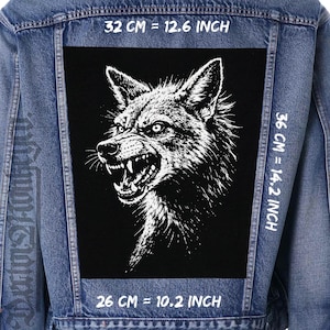 Peut inclure: Veste en jean bleue avec un écusson noir orné d'une illustration blanche détaillée d'un loup menaçant. L'écusson mesure 26 cm sur 32 cm, et les dimensions de la veste sont de 36 cm.