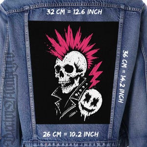 Peut inclure: Une veste en jean bleu avec un grand écusson rectangulaire noir au dos. L'écusson représente un crâne blanc avec une crête rose vif, portant une veste en cuir cloutée, à côté d'un visage souriant blanc. Dimensions : 32 cm par 36 cm.