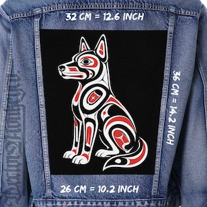 May include: A blue denim jacket featuring a large rectangular patch on the back with a stylized dog illustration in black, white, and red. The patch measures 12.6 inches by 14.2 inches, with a bottom width of 10.2 inches, as indicated by text.