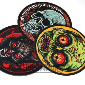 May include: Three round, black-edged patches with spooky illustrations. One features a skull, another a snarling wolf, and the third a zombie-like face. The top patch has the text "vectormonkeyco.etsy.com" in a circular design.