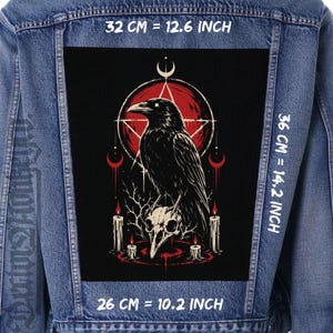 May include: A blue denim jacket featuring a large rectangular back patch with a black raven perched on a skull. The graphic includes a red pentagram, crescent moons, and lit candles. Text indicates dimensions of 32 cm by 36 cm by 26 cm.