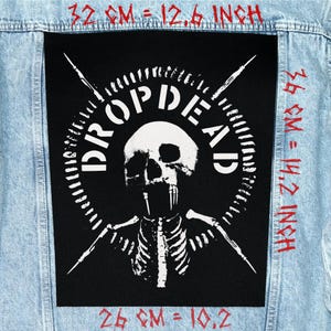 Puede incluir: Un parche negro con un diseño de calavera y esqueleto y las palabras "DROP DEAD". El parche está sobre una chaqueta vaquera azul claro. El parche mide 32 cm de ancho por 36 cm de alto.