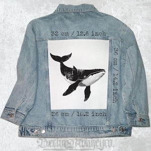 Può includere: Giacca di jeans azzurra con una grande grafica di balena in bianco e nero sul retro. La grafica misura 32 cm di larghezza per 36 cm di altezza. La giacca ha un design classico con chiusure a bottone.