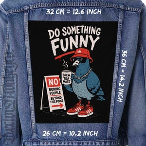 Puede incluir: Una chaqueta de mezclilla azul con un parche rectangular grande en la espalda. El parche muestra una paloma con un sombrero de pescador rojo, gafas de sol y una cadena, sosteniendo una taza que dice BREW TEA MATE. Un letrero dice NO BORING PEOPLE BEYOND THIS POINT. Dimensiones: 32 cm por 36 cm.