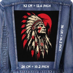 May include: A blue denim jacket featuring a large rectangular patch on the back. The patch displays a graphic of a person in a feathered headdress against a red sun. Text indicates dimensions of 32 cm by 36 cm by 26 cm, or 12.6 by 14.2 by 10.2 inches.