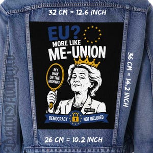 May include: A blue denim jacket featuring a large rectangular back patch with a black background. The patch displays a graphic of a woman wearing a crown, holding a mirror with the text 'MY WAY OR THE HIGHWAY'. Text includes 'EU? MORE LIKE ME-UNION', 'VON DER LEYEN', and 'DEMOCRACY NOT INCLUDED' with a lock icon. Dimensions are 12.6 inches by 14.2 inches by 10.2 inches.